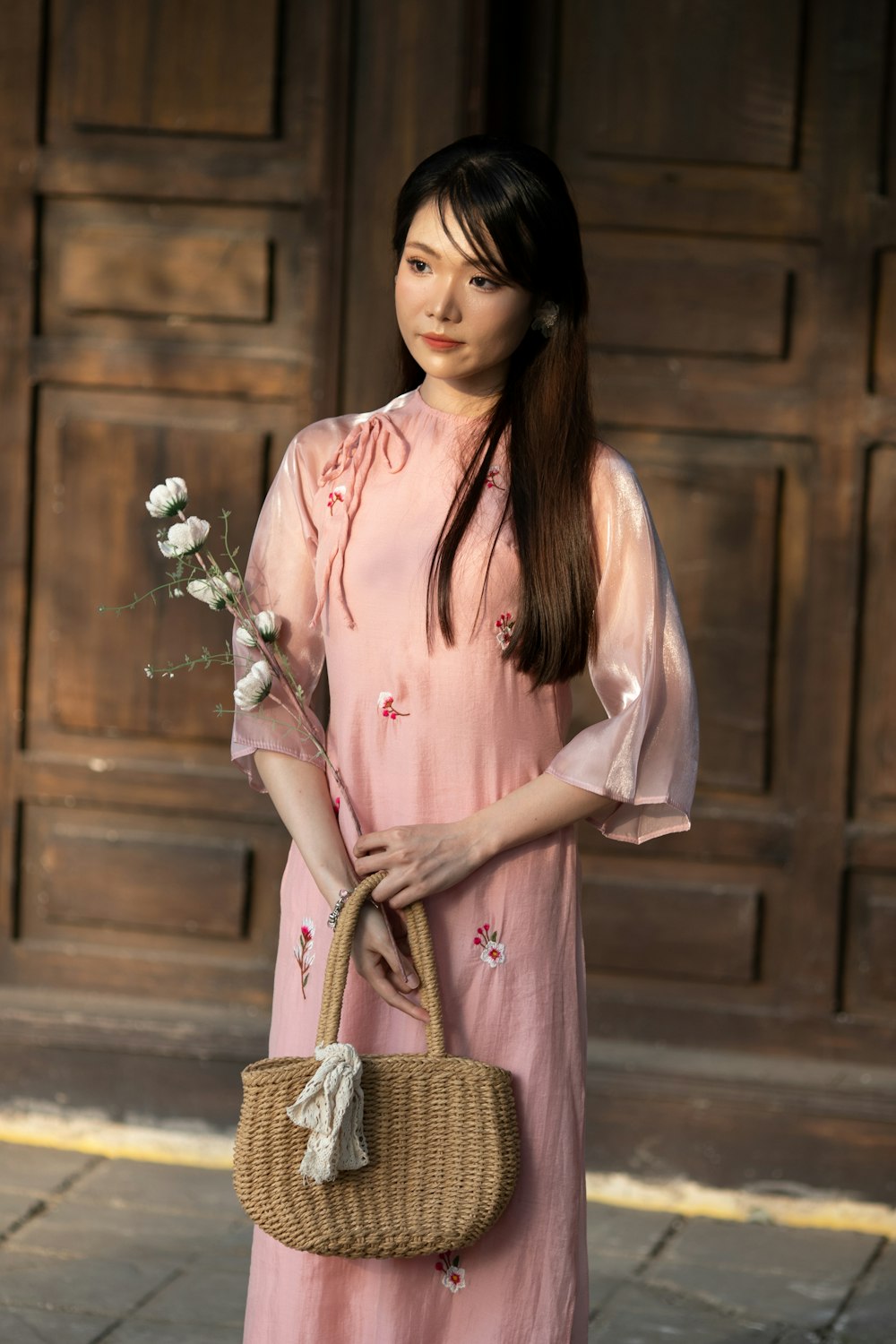 a woman in a pink dress holding a wicker basket