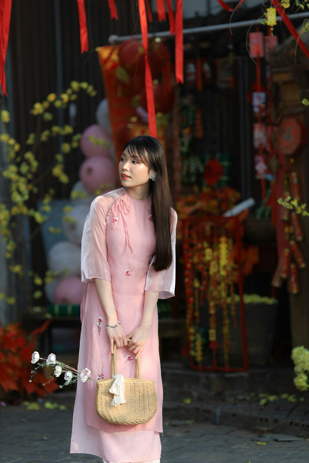 a woman in a pink dress holding a straw bag