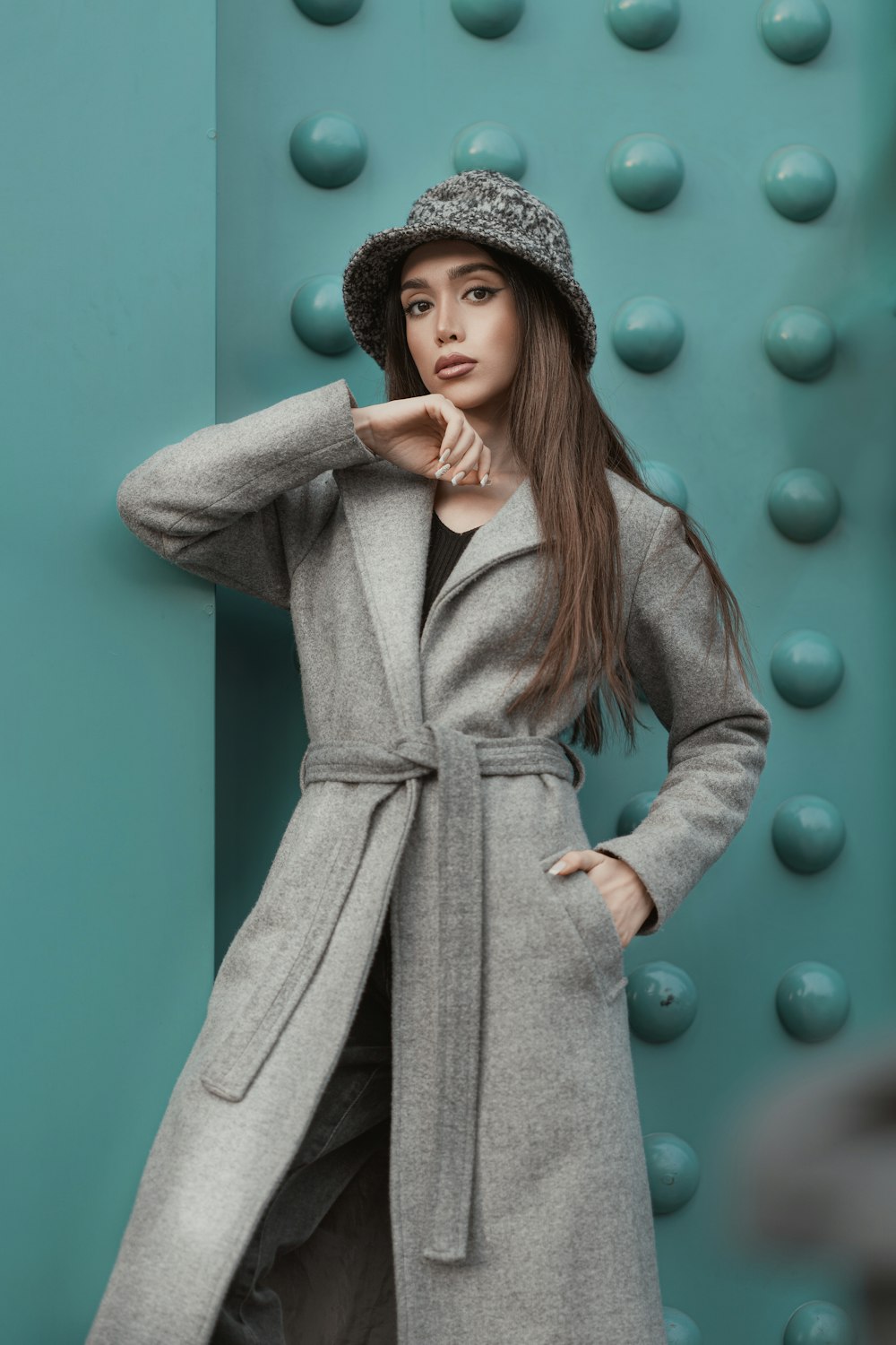 a woman in a coat and hat posing for a picture