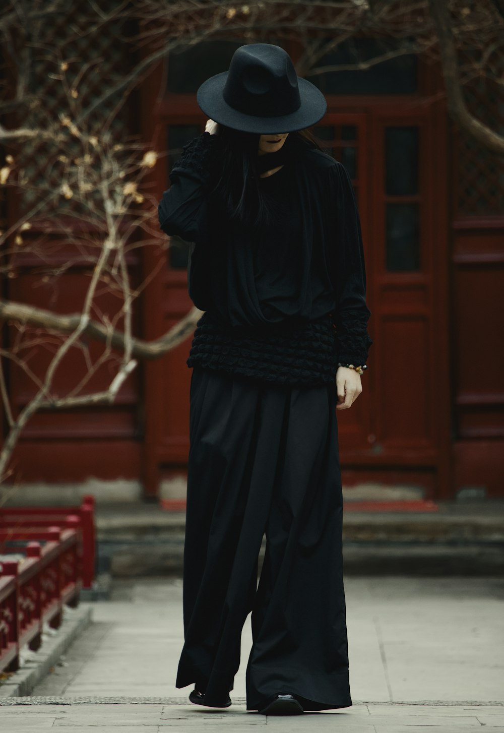 a woman wearing a black hat and long black pants