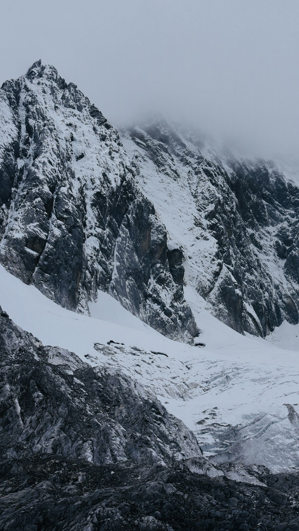 a mountain covered in snow and surrounded by clouds