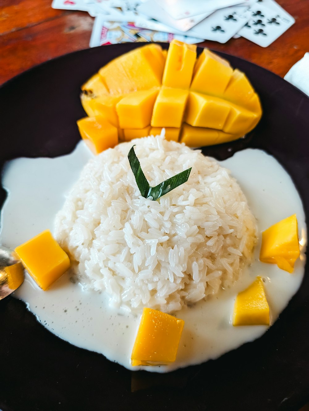 a black plate topped with rice and mango slices