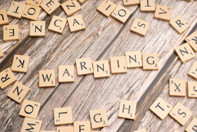scrabble tiles spelling warning on a wooden surface