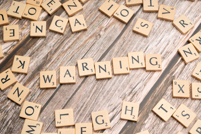 scrabble tiles spelling warning on a wooden surface