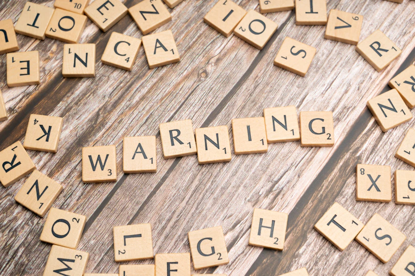 scrabble tiles spelling warning on a wooden surface