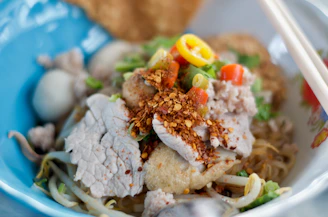 a close up of a bowl of food with chopsticks