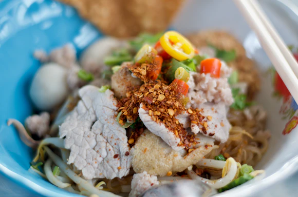 a close up of a bowl of food with chopsticks