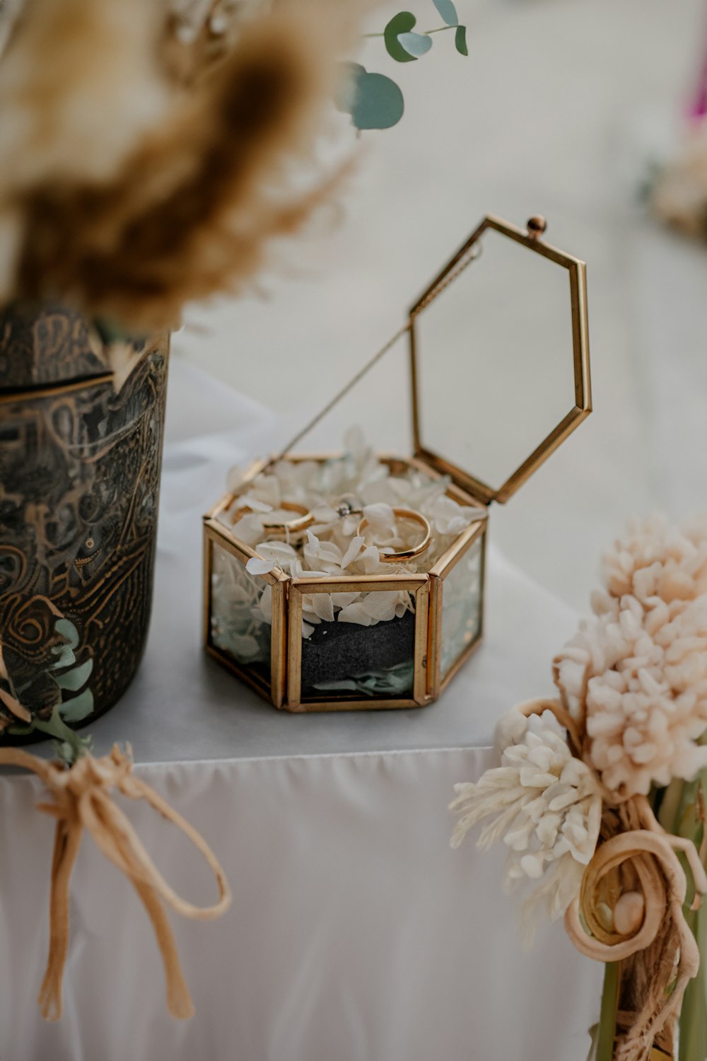 a table topped with a box and a vase filled with flowers