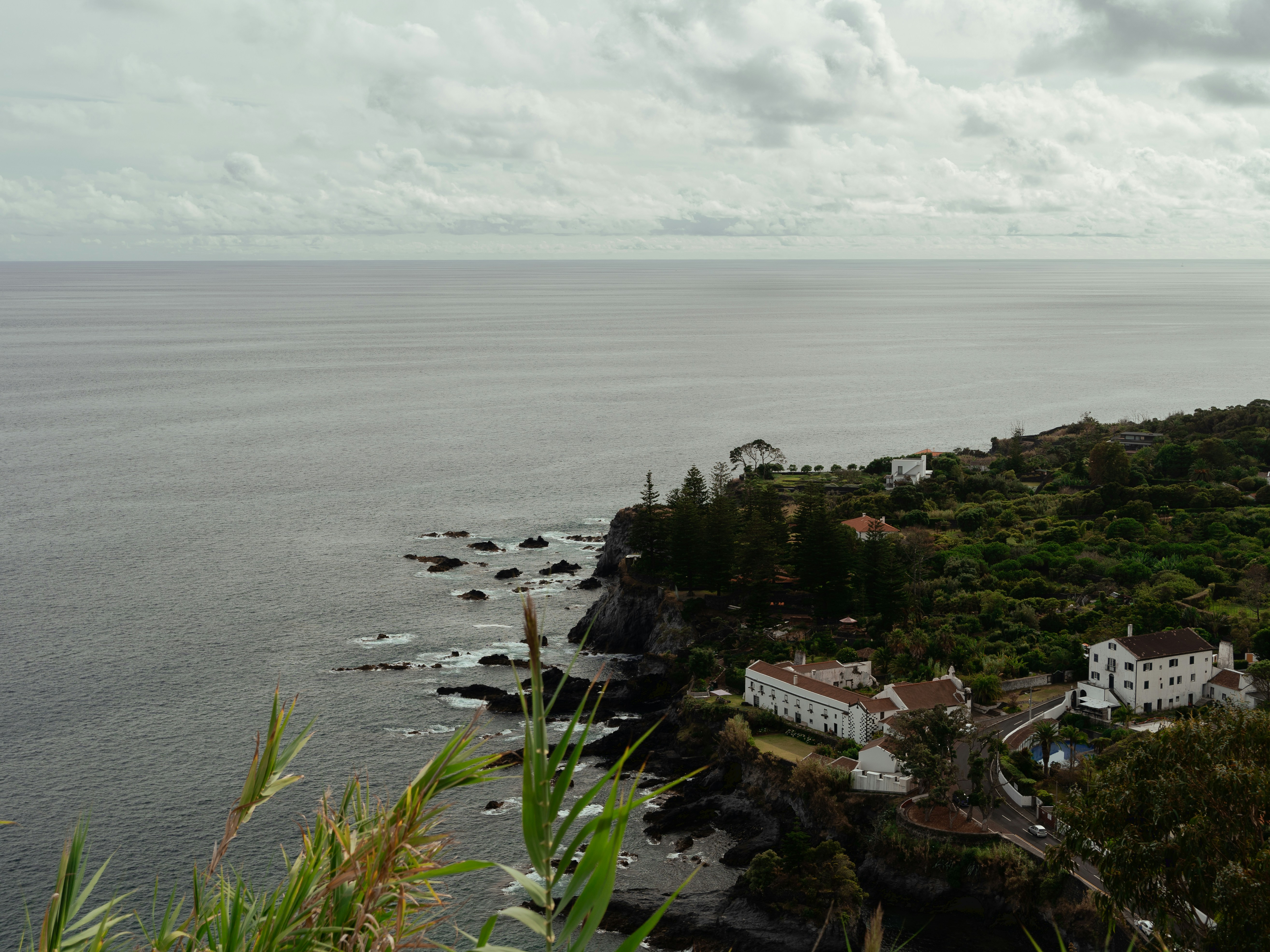 a large body of water next to a lush green hillside, View of the town Água de Pau belonging to the municipality of Lagoa, located on the Island of São Miguel, Autonomous Region of Azores.