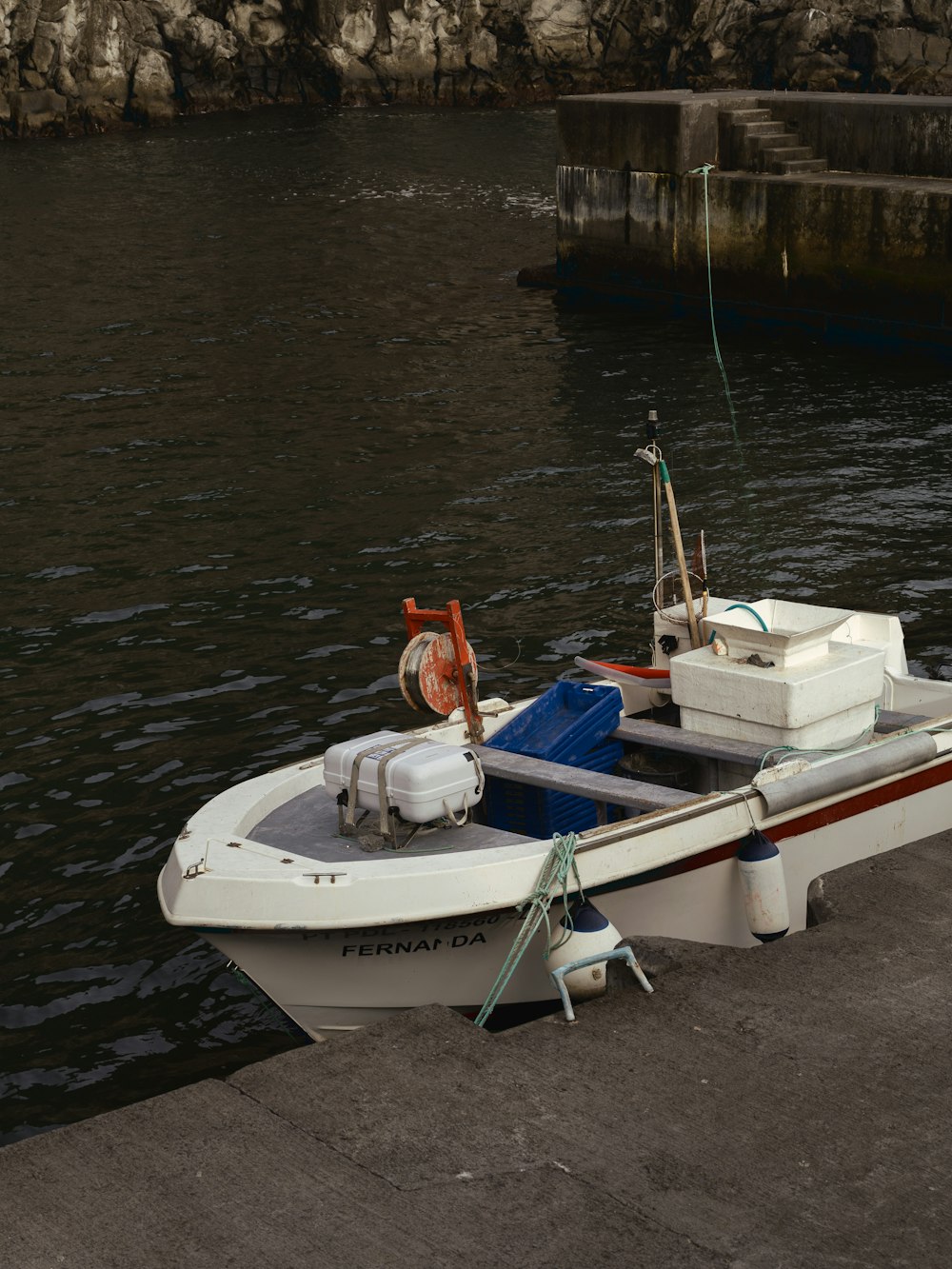 a small white boat tied to a dock