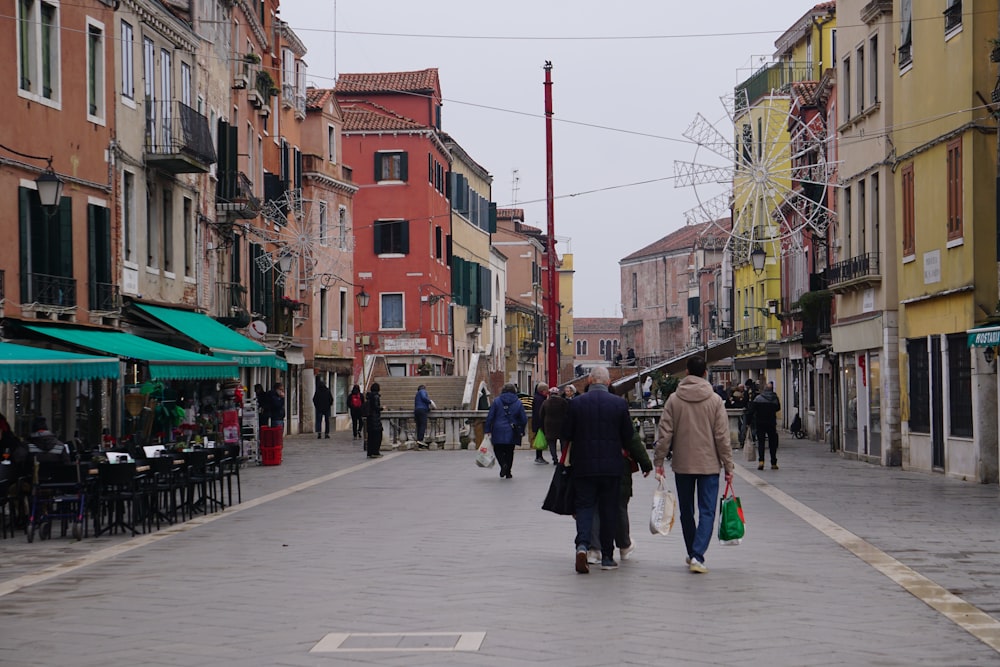 a group of people walking down a street next to tall buildings