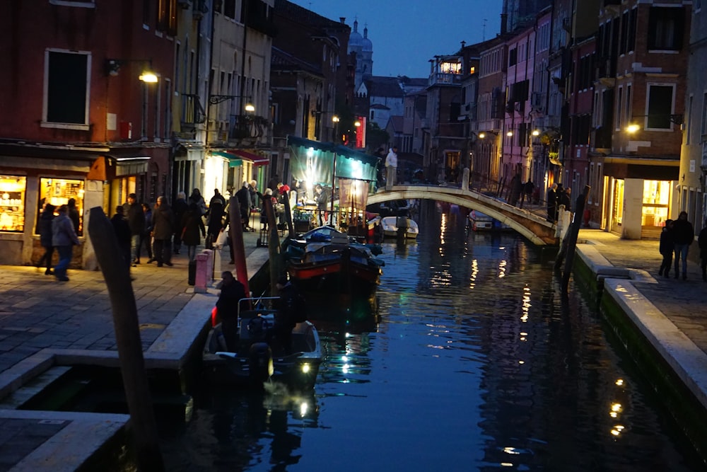 un canal en una ciudad por la noche con un puente sobre él