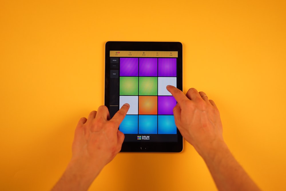 a person holding a tablet with a colorful cube on it