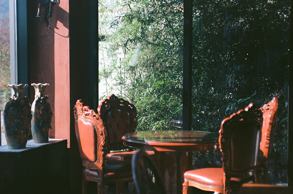 a room with a table, chairs, and vases