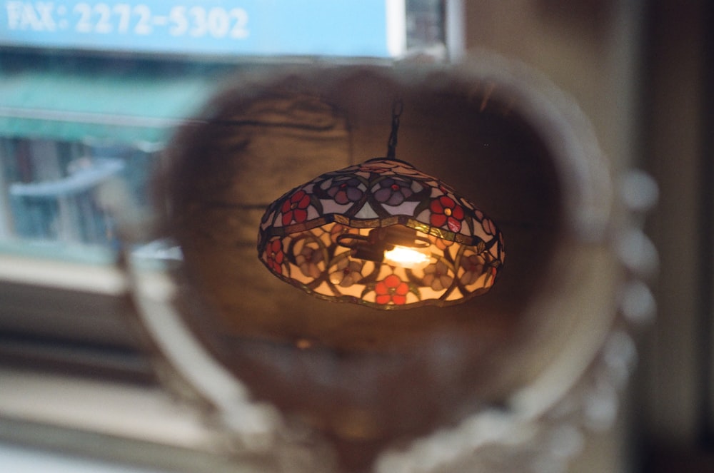 a stained glass lamp hanging from the side of a window