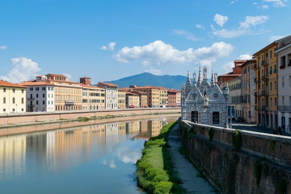 A river running through a city next to tall buildings — Pisa, Italy