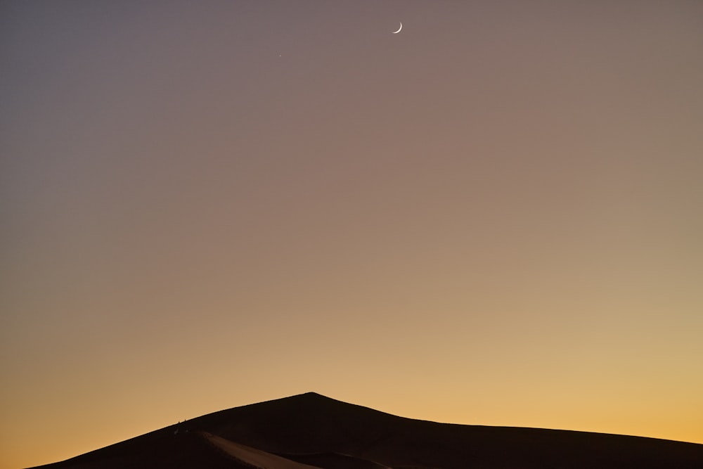 the moon is setting in the sky over the desert