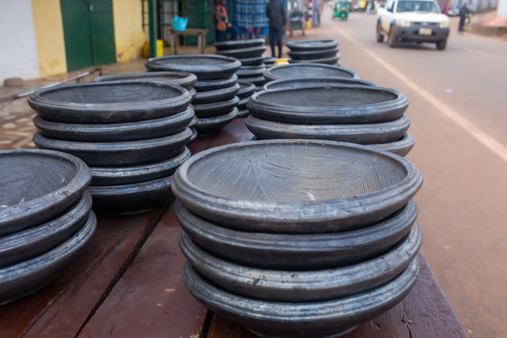 a group of black plates sitting on top of a wooden table
