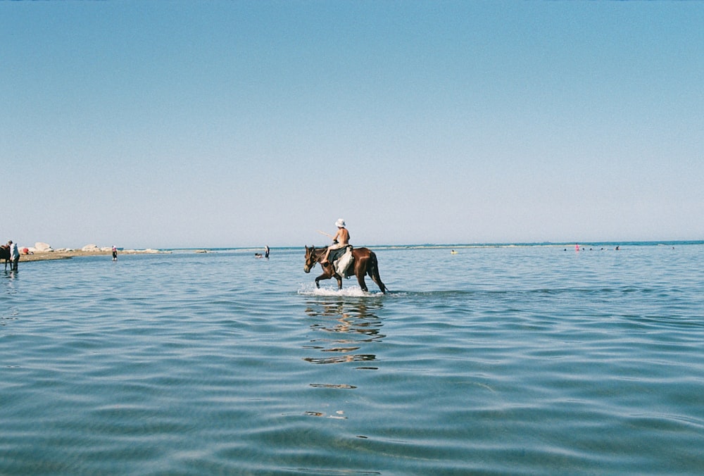 a person riding a horse across a body of water