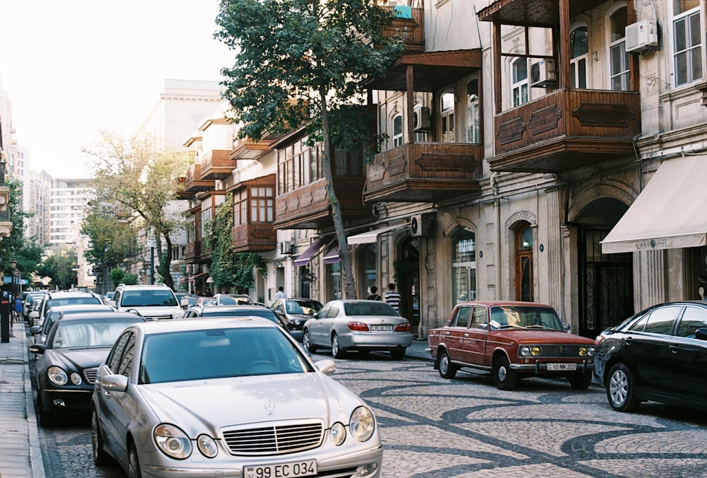 a street filled with lots of parked cars next to tall buildings