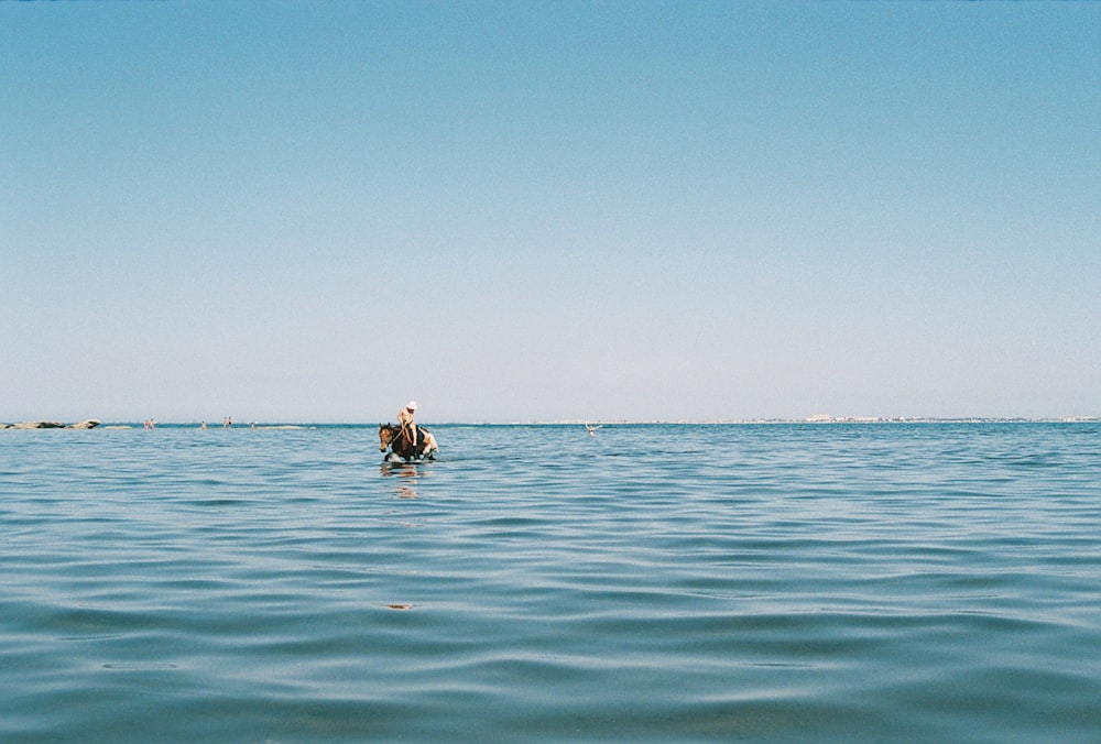 a person in a body of water with a boat in the background