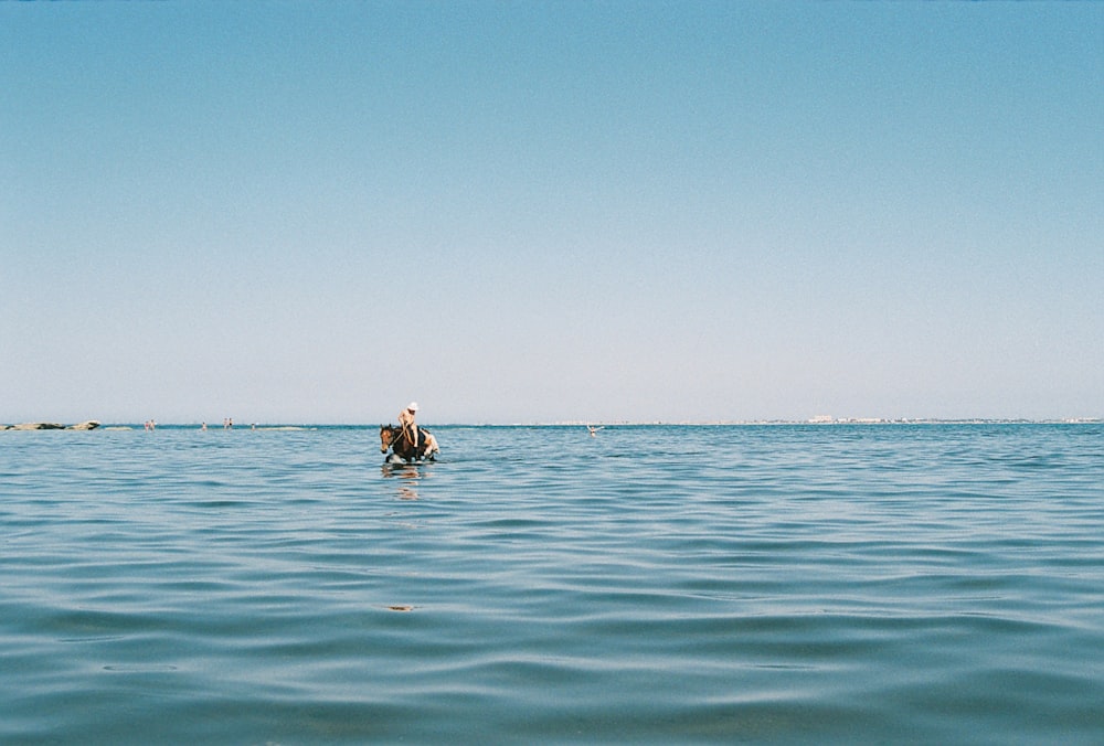 eine Person in einem Gewässer mit einem Boot im Hintergrund