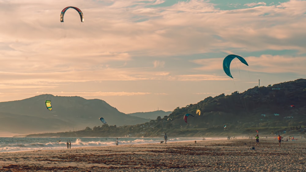 a group of people on a beach flying kites
