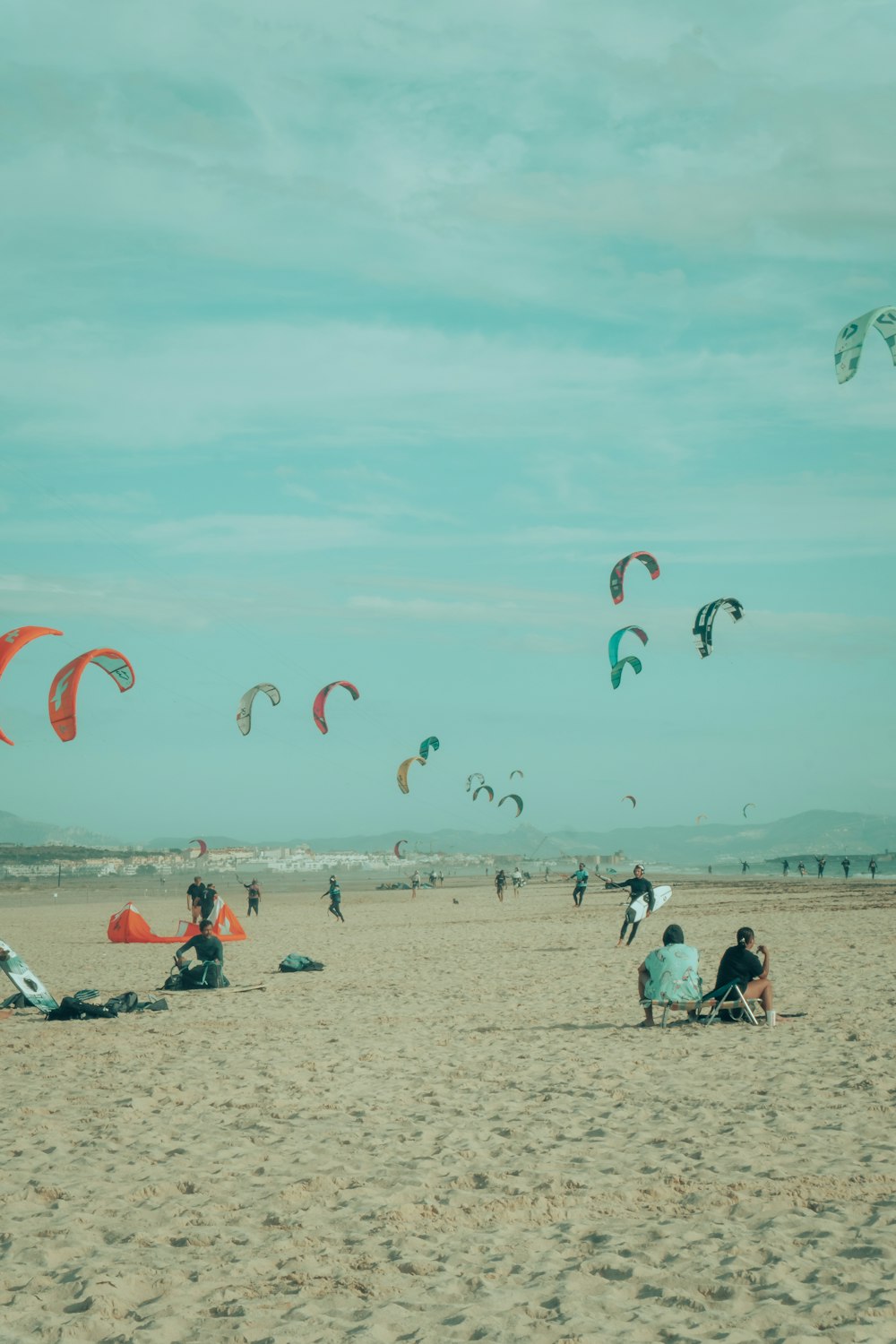 a group of people sitting on top of a sandy beach