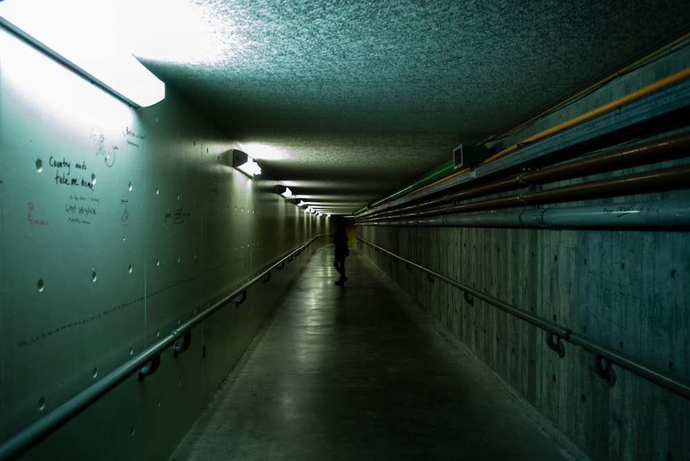 uma pessoa andando por um longo corredor escuro
