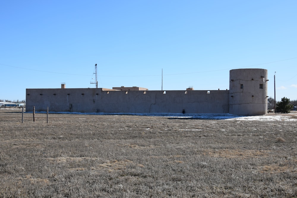 a large building sitting in the middle of a dry grass field