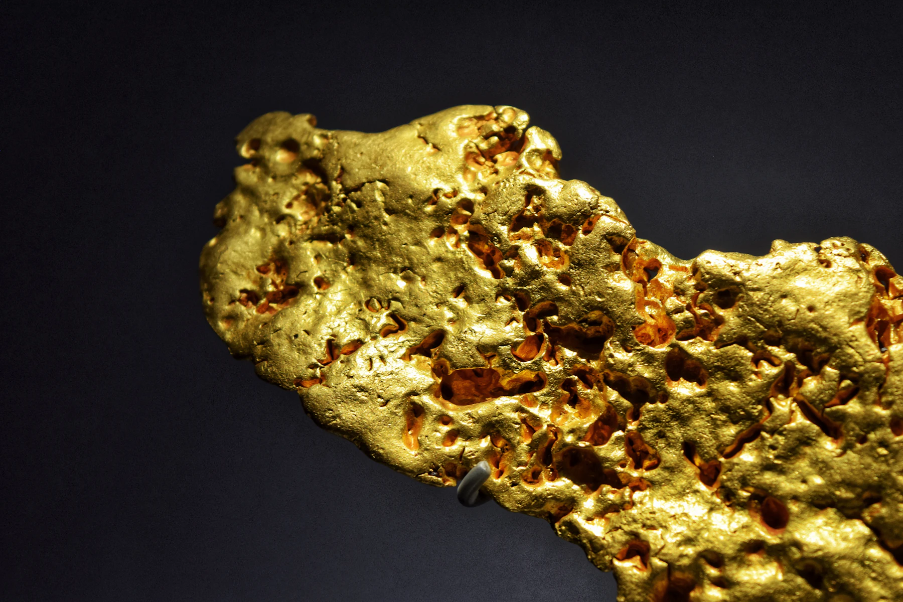 Close-up of a natural gold nugget against a dark background