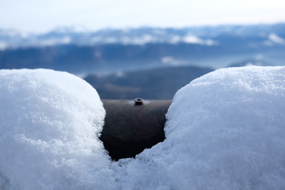 a pipe sticking out of the snow with mountains in the background