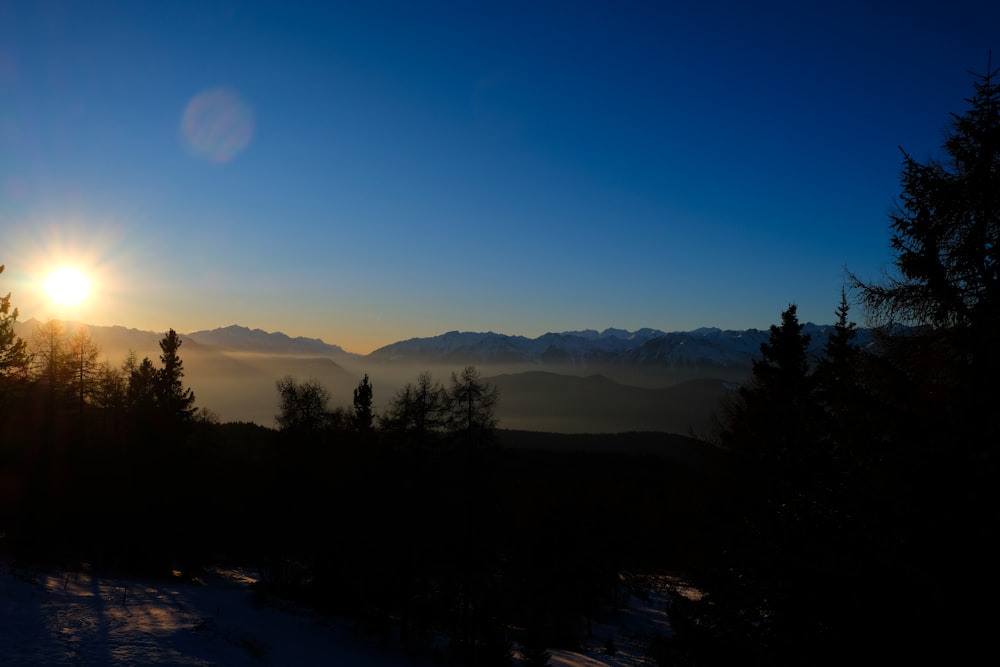 the sun is setting over a mountain range