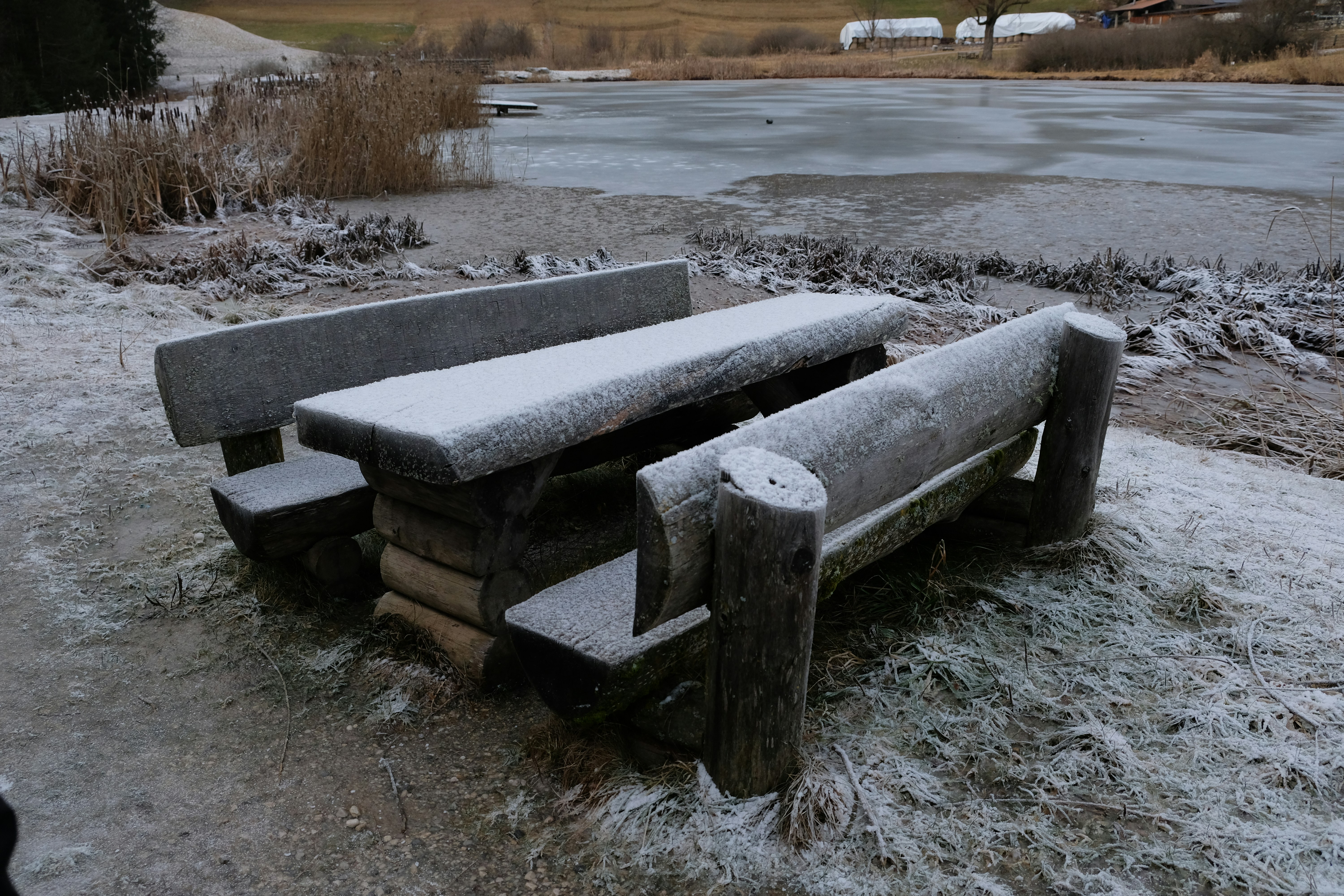 a wooden bench sitting on top of a snow covered field