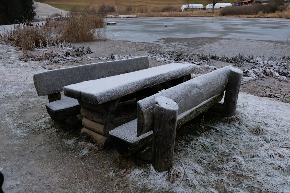 a wooden bench sitting on top of a snow covered field
