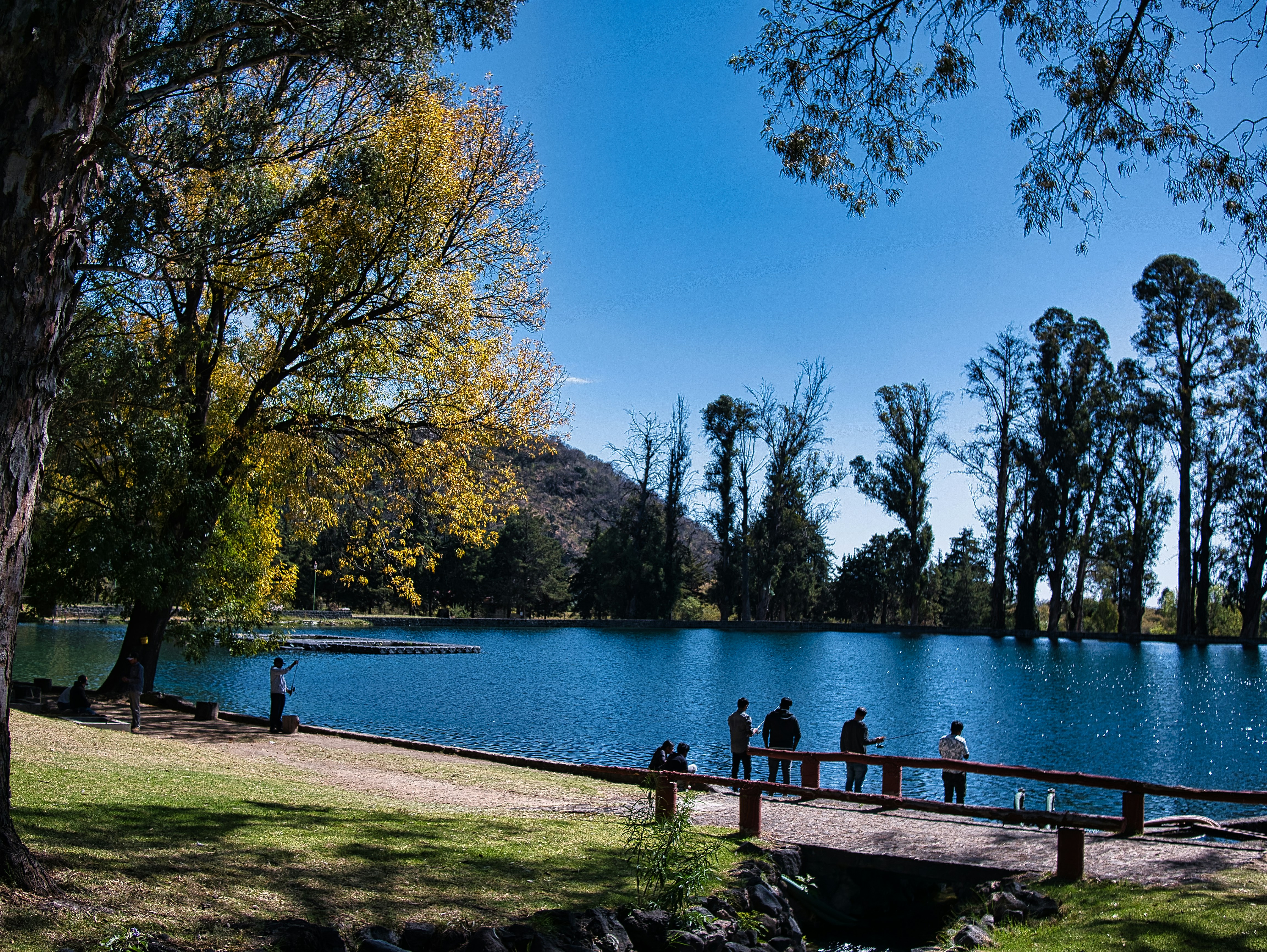 a group of people standing on a pier next to a lake