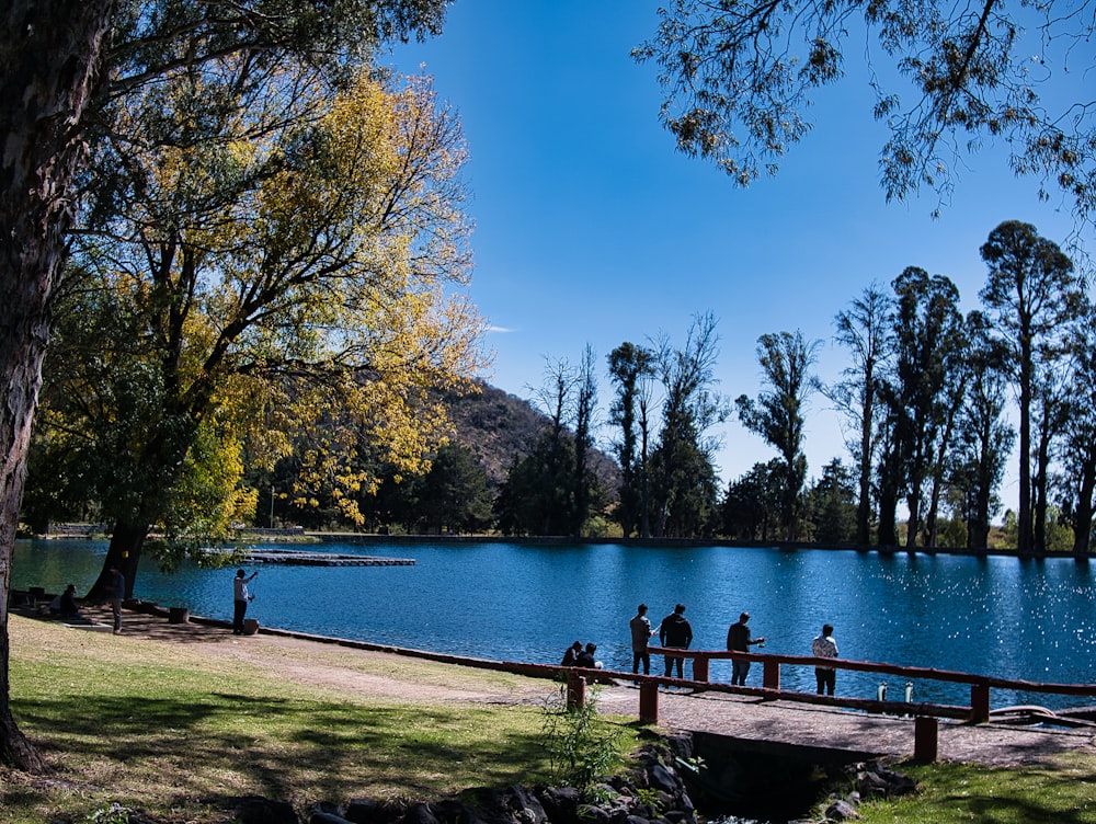 a group of people standing on a pier next to a lake