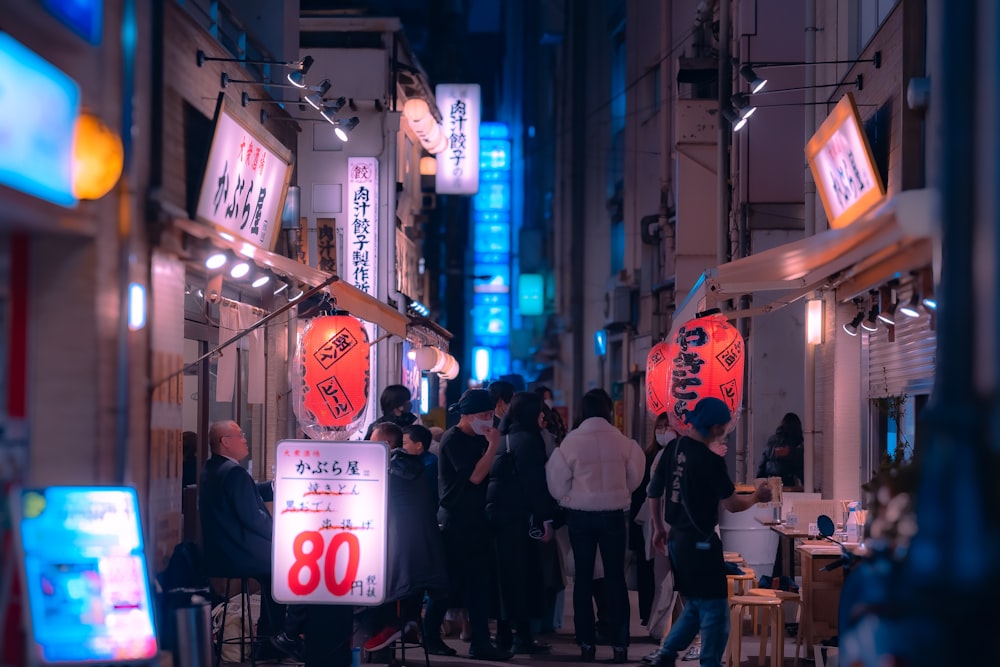 a group of people walking down a street at night