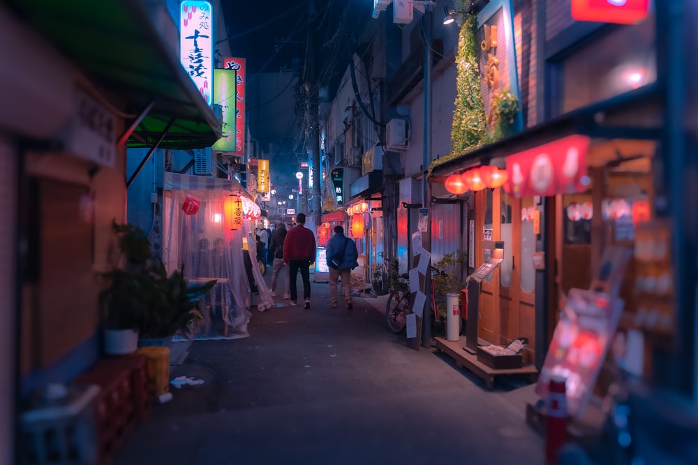 people walking down a narrow street at night