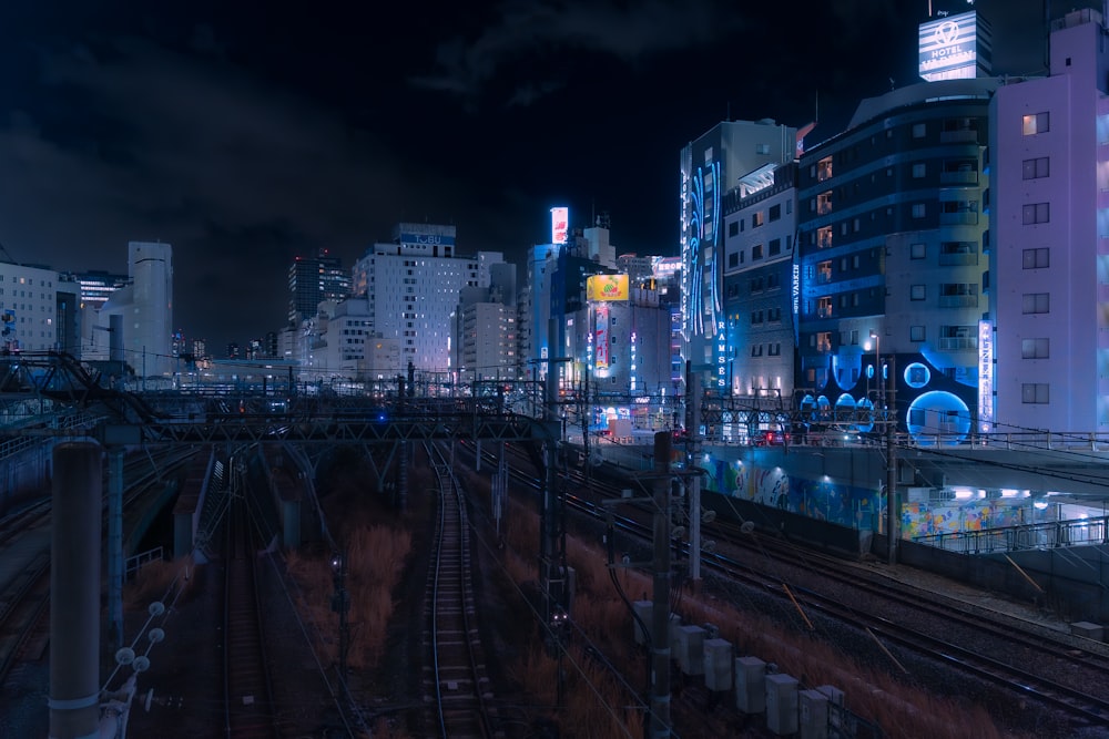 une ville la nuit avec un train sur les rails