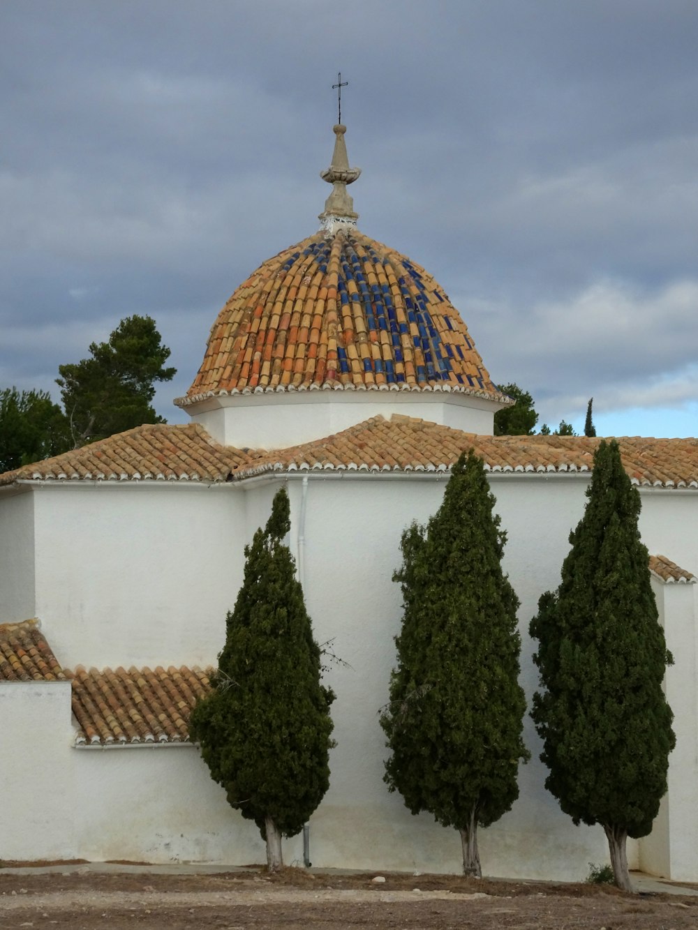 a white building with a dome and trees in front of it