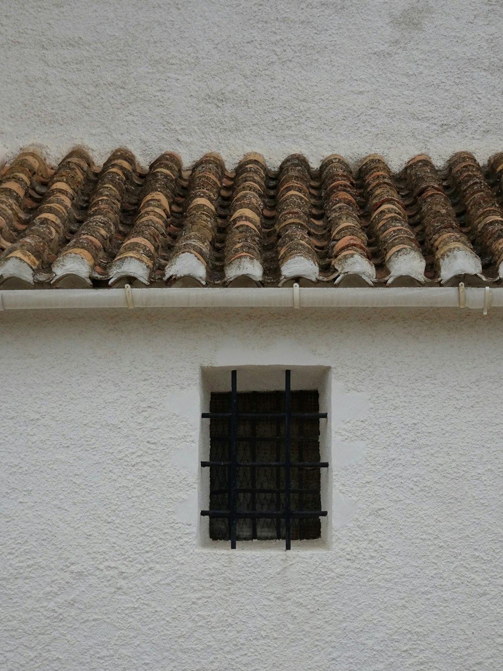 a white building with a window and tiled roof