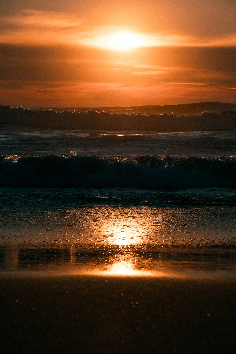 the sun is setting over the ocean on a beach