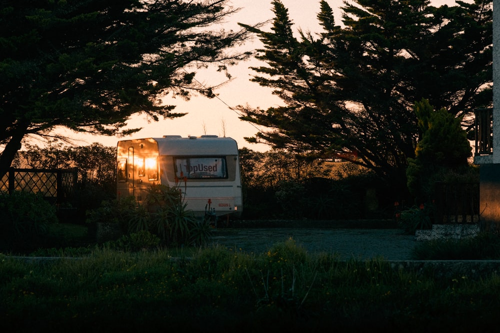 a trailer parked in front of some trees at sunset