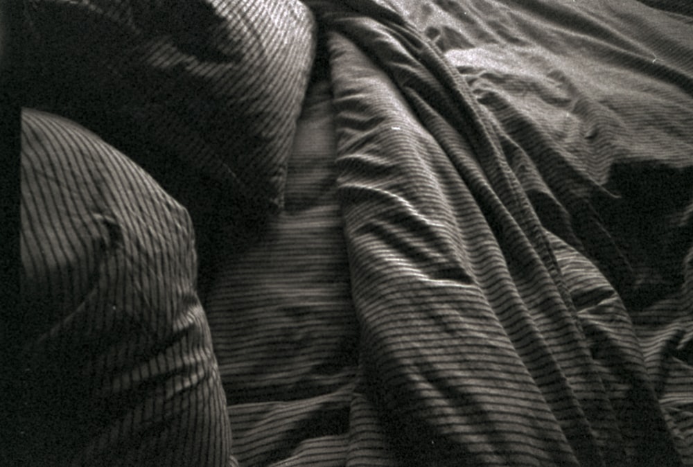 a black and white photo of a person sleeping in a bed