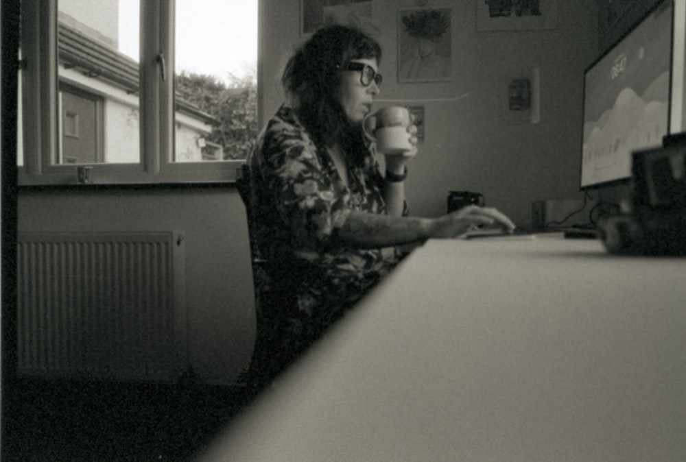 a woman sitting at a desk with a cup of coffee