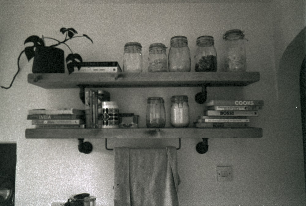 a shelf with jars, books, and other items on it