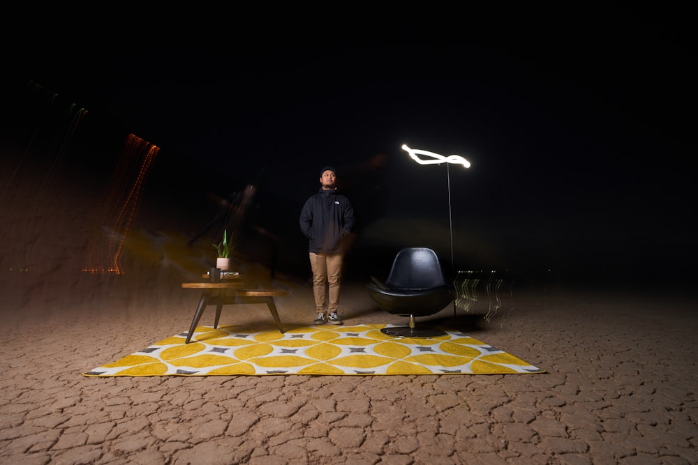 a man standing in the dark next to a chair