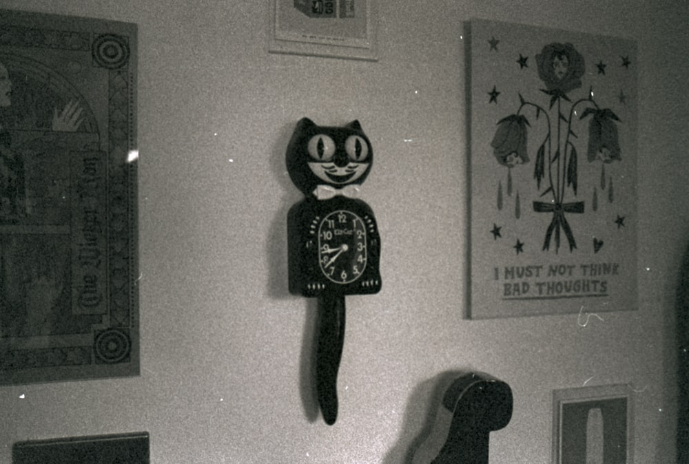 a black and white photo of a cat clock on a wall