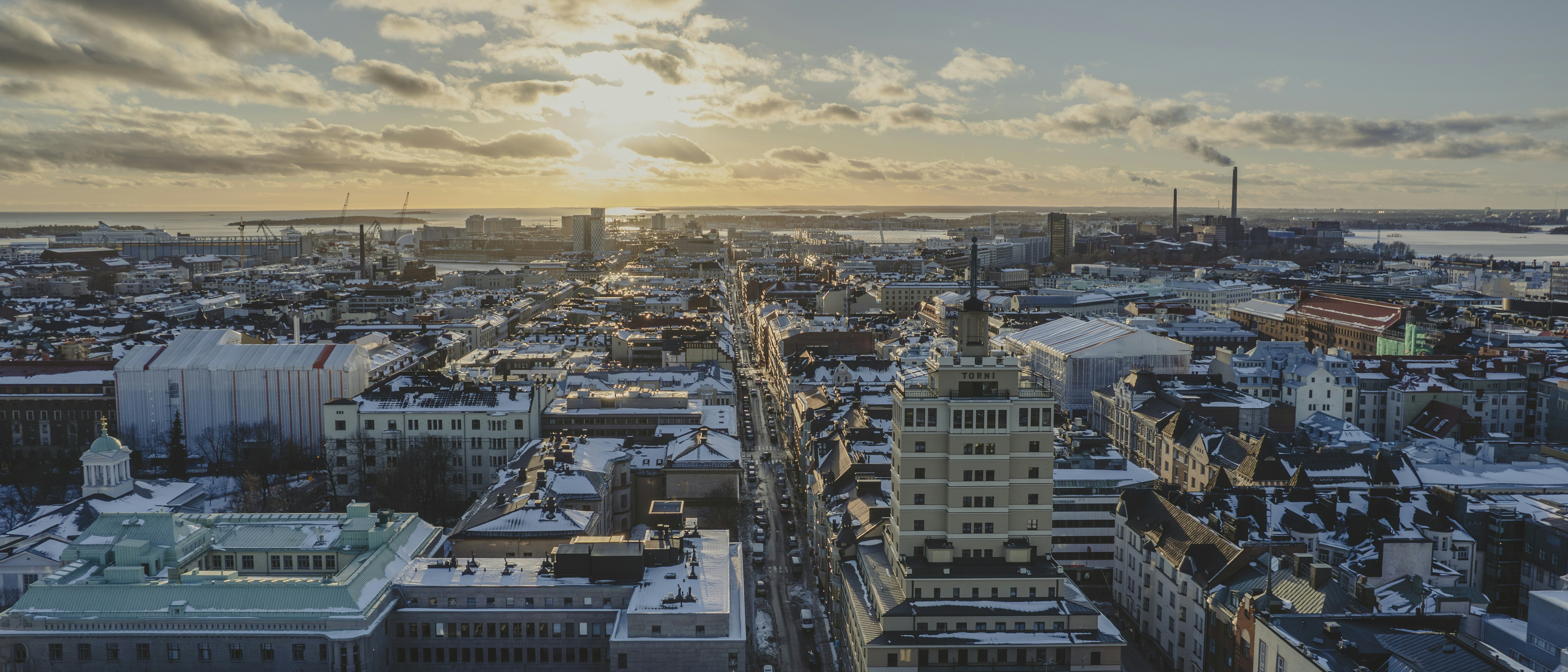 the sun is setting over a city with tall buildings